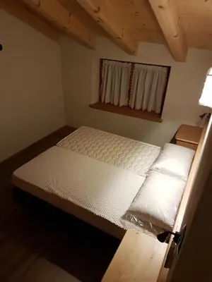 a large bed in a room with a window at Casa De Sandre in San Vito di Cadore