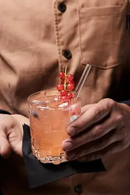a person holding a drink with cherries on it at Boutique Hotel Badhaus in Bressanone