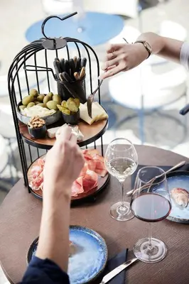 a table with a plate of food and a person reaching for a wine glass at Boutique Hotel Badhaus in Bressanone