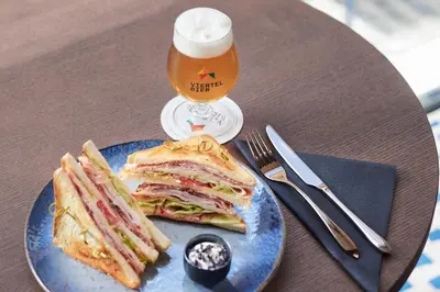 a blue plate with a sandwich and a glass of beer at Boutique Hotel Badhaus in Bressanone