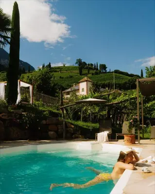 a woman laying in a swimming pool at Langenmantel Historic Suites in Termeno