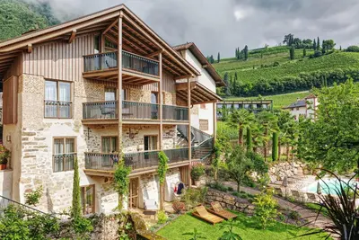 an apartment building with balconies and a yard at Langenmantel Historic Suites in Termeno