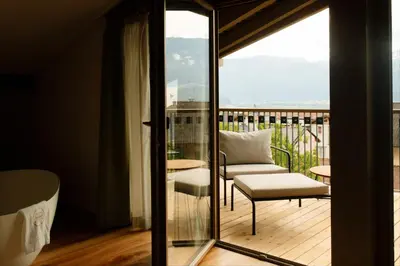 a room with a balcony with a chair and a window at Langenmantel Historic Suites in Termeno