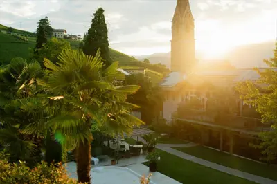 a church with a palm tree in front of it at Langenmantel Historic Suites in Termeno