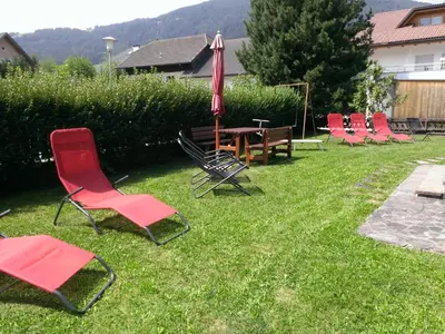 a group of chairs and an umbrella in the grass at Ferienwohnungen Schnarf in Valdaora