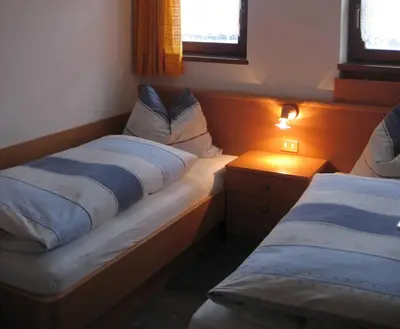 a bedroom with two beds and a lamp on a table at Ferienwohnungen Schnarf in Valdaora