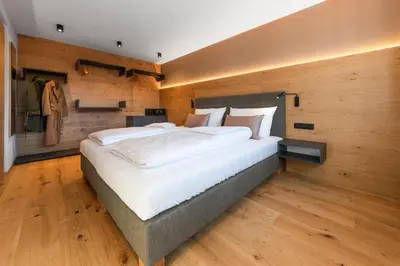 a large bed in a room with wooden walls at Rienz Alpine City Suites in Brunico