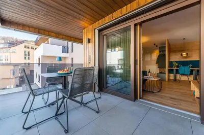 a patio with two chairs and a table on a balcony at Rienz Alpine City Suites in Brunico
