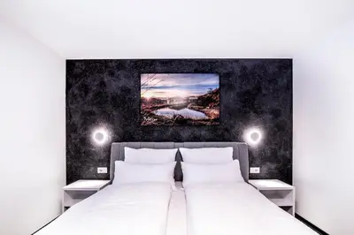 a bedroom with a white bed with two night stands at Apartmenthouse STERN in Vipiteno