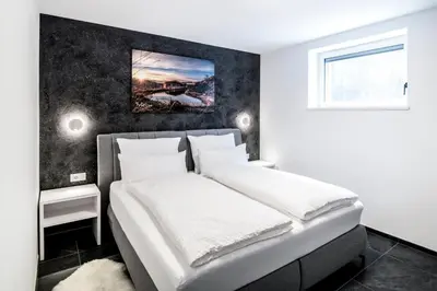a bedroom with a large bed with white sheets at Apartmenthouse STERN in Vipiteno