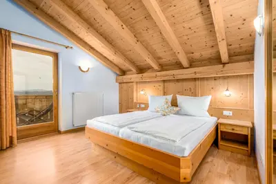 a bed in a room with a wooden ceiling at Formsunhof in Siusi