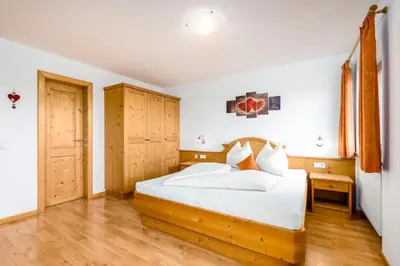 a bedroom with a bed with white sheets and wooden floors at Formsunhof in Siusi