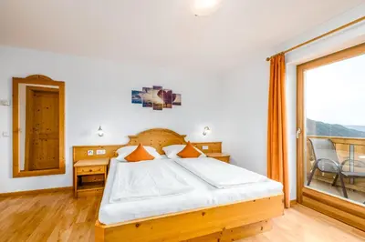 a bedroom with a bed and a large window at Formsunhof in Siusi