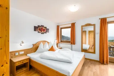 a bedroom with a bed with white sheets and a mirror at Formsunhof in Siusi