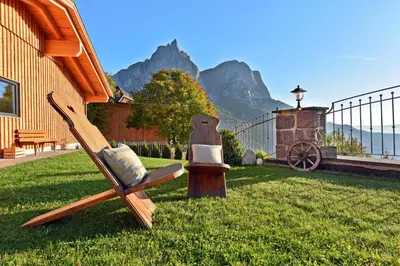 a chair sitting in the grass with mountains in the background at Formsunhof in Siusi
