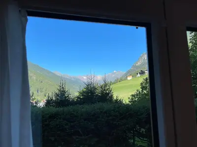 a window view of a green field and mountains at Apartment Weisswand in Colle Isarco