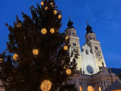 a christmas tree in front of a building with a clock tower at Apartment Weisswand in Colle Isarco