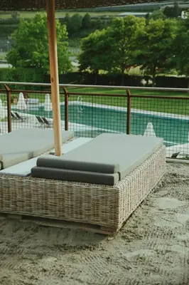 a wicker bed sitting on the ground next to a pool at Solterra Poolhouse 2 in Tisens