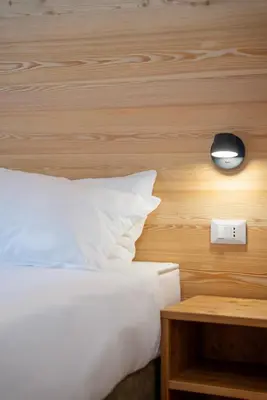 a bedroom with a bed and a lamp and a table at Chalet Le Grazie in Le Grazie