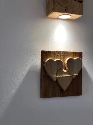 two hearts hanging on a wall with a light at Chalet Le Grazie in Le Grazie