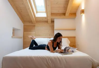 a woman laying on a bed with a laptop at Chalet Le Grazie in Le Grazie