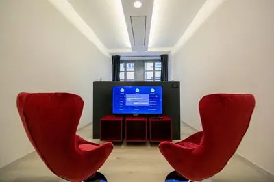 two red chairs sitting in front of a television at Apartment Bolzano in Bolzano