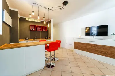 a kitchen with a bar with red chairs and a tv at Apartment Bolzano in Bolzano
