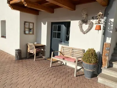 a porch with a bench and a table and a door at Apartment Kesselkogel - Rosenheim Apartments in Tires