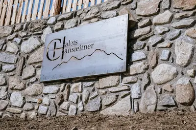 a sign on the side of a stone wall at Chalets Hansleitner in Terento