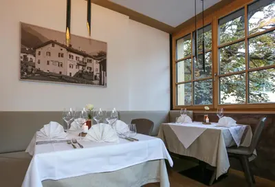 two tables in a restaurant with white table cloths and glasses at Hotel Gasthof Höllriegl in Sarntal