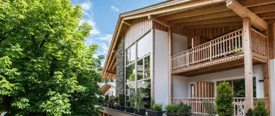 an apartment building with balconies and trees at Hotel Gasthof Höllriegl in Sarntal