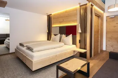 a bedroom with a large bed with a wooden headboard at Hotel Gasthof Höllriegl in Sarntal