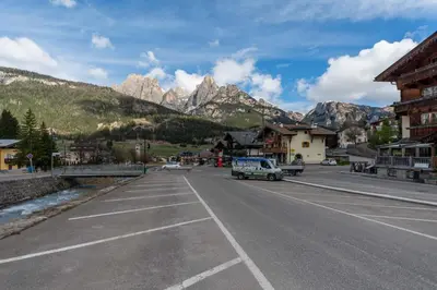 an empty street in a town with mountains in the background at Casa Baranci in Pozza di Fassa