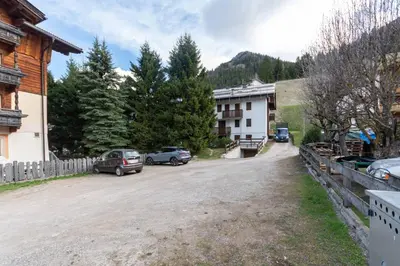 a dirt road with cars parked in front of a house at Casa Baranci in Pozza di Fassa