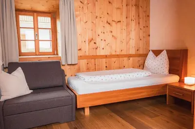 a bedroom with a bed and a couch and a window at Huberhof in Naz-Sciaves