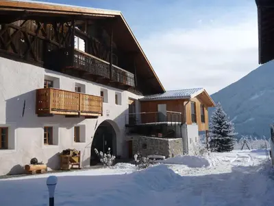 a building with a balcony in the snow at Huberhof in Naz-Sciaves