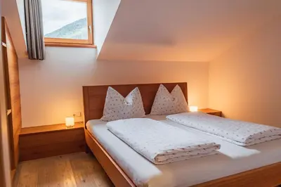 a bedroom with a bed with white sheets and a window at Huberhof in Naz-Sciaves