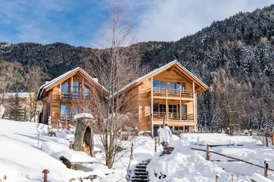 a log cabin in the snow in front of a mountain at Alma Apartments in Luson
