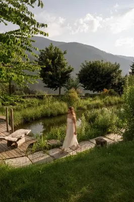 a woman in a white dress walking by a river at Alma Apartments in Luson