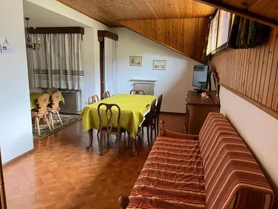 a dining room with a table and a couch at CASA PINUCCIA MANSARDA in Predazzo