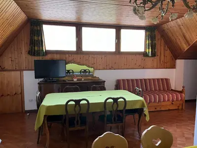 a living room with a table and a couch at CASA PINUCCIA MANSARDA in Predazzo
