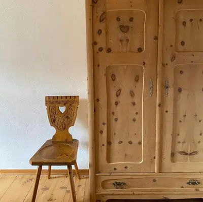 a wooden cabinet next to a chair and a vase at Farmhouse with a stunning view over the dolomites in Villnoss