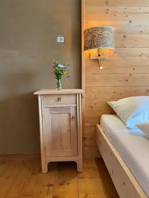 a bed with a table with a vase of flowers on it at Farmhouse with a stunning view over the dolomites in Villnoss