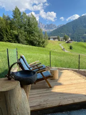 a bench on a wooden deck with a view of a mountain at Farmhouse with a stunning view over the dolomites in Villnoss