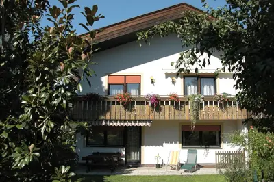 a white house with a balcony with a deck at haus e Apartment 1 in Lana