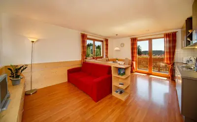 a living room with a red couch in a kitchen at Beimsteinhof in Verano