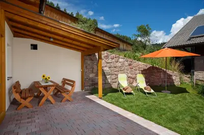 a patio with a table and chairs and an umbrella at Beimsteinhof in Verano