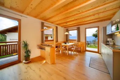 a kitchen and dining room with wooden ceilings and windows at Beimsteinhof in Verano