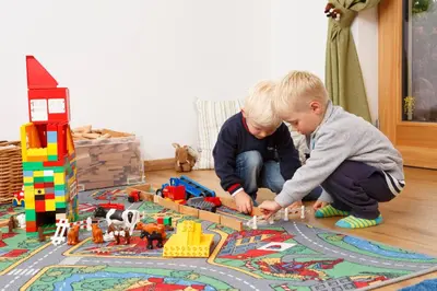 two young boys playing with toy trains on a rug at Beimsteinhof in Verano