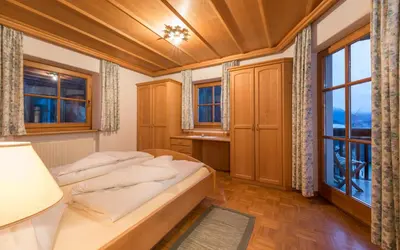a bedroom with a bed and a large window at Lusina Apartments in Luson
